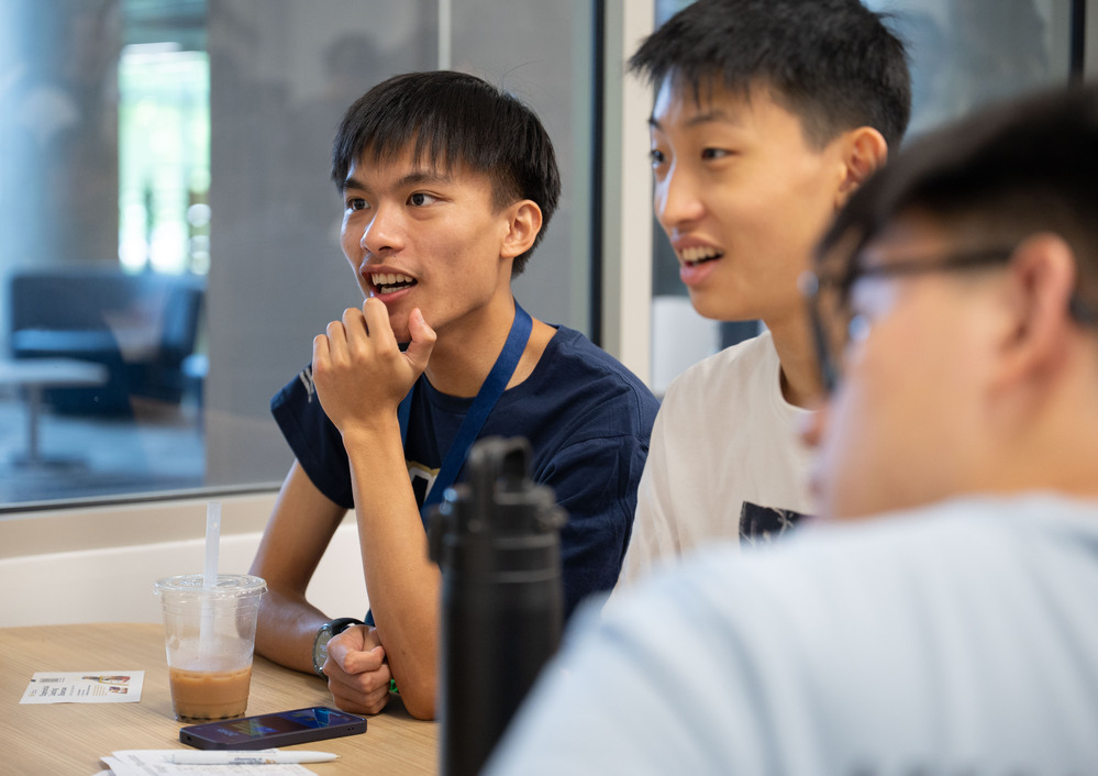 3 students sitting around a table chatting